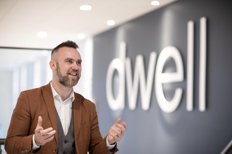 Employee in front of the Dwell logo